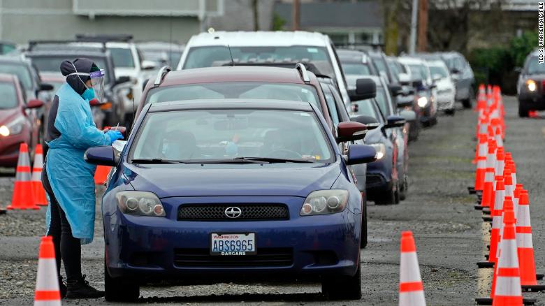 A worker at a drive-up COVID-19 testing clinic  administers PCR coronavirus tests, Tuesday, Jan. 4, 2022, in Puyallup, Wash., south of Seattle. People using the facility, which is being run by the Pierce County Dept. of Emergency Management, faced waits of several hours Tuesday for testing. (AP Photo/Ted S. Warren)